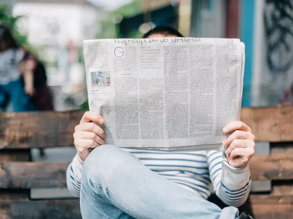 Someone on a bench reads a newspaper.