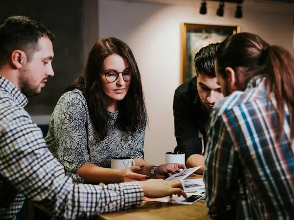 Four people look at papers together at a table.